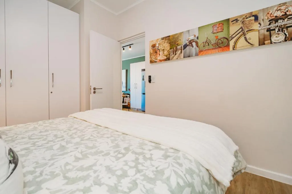 Bright bedroom with queen bed, built-in wardrobes, and decorative wall art