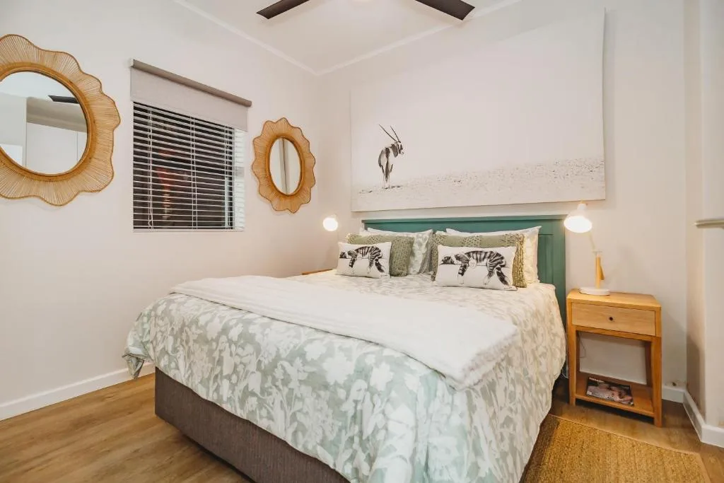 Bright bedroom with green headboard, patterned bedding, and safari artwork