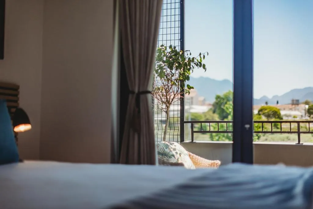 Modern bedroom with mountain views through large windows and balcony doors