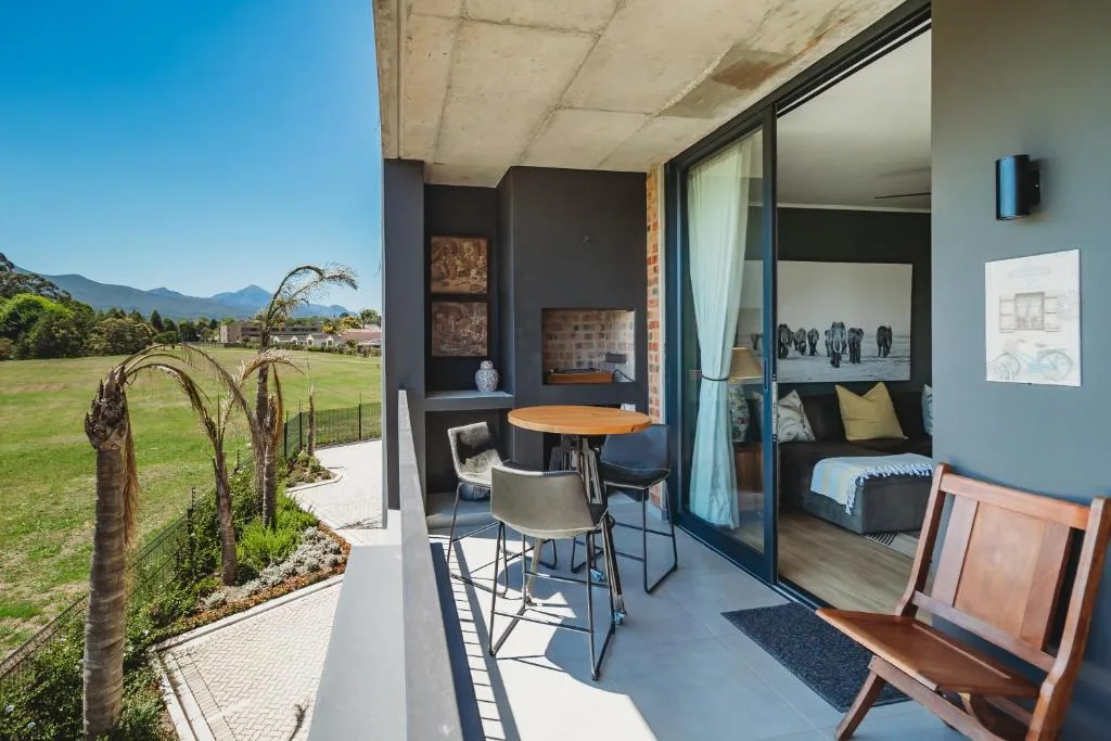 Modern patio with dining table overlooking green meadow and mountains