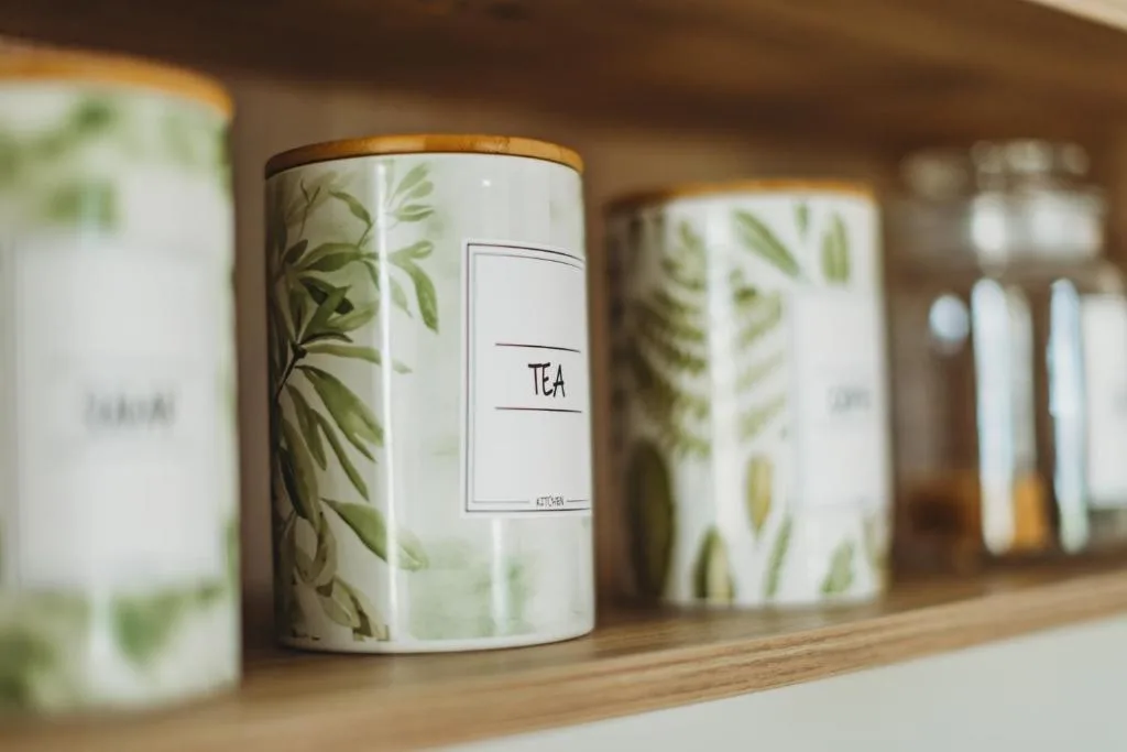 Decorative tea canisters with botanical leaf designs on kitchen shelf