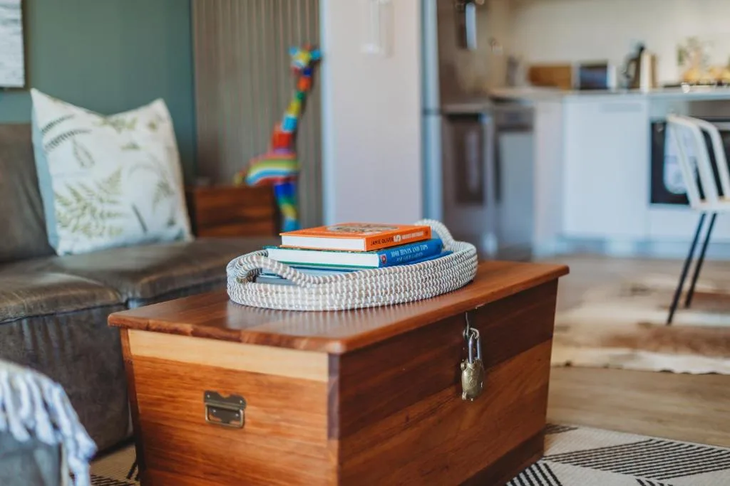 Wooden trunk with stacked books and woven basket in bright living area