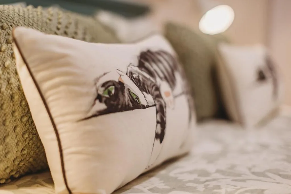 Close-up of decorative pillow with cat illustration on bedroom bed