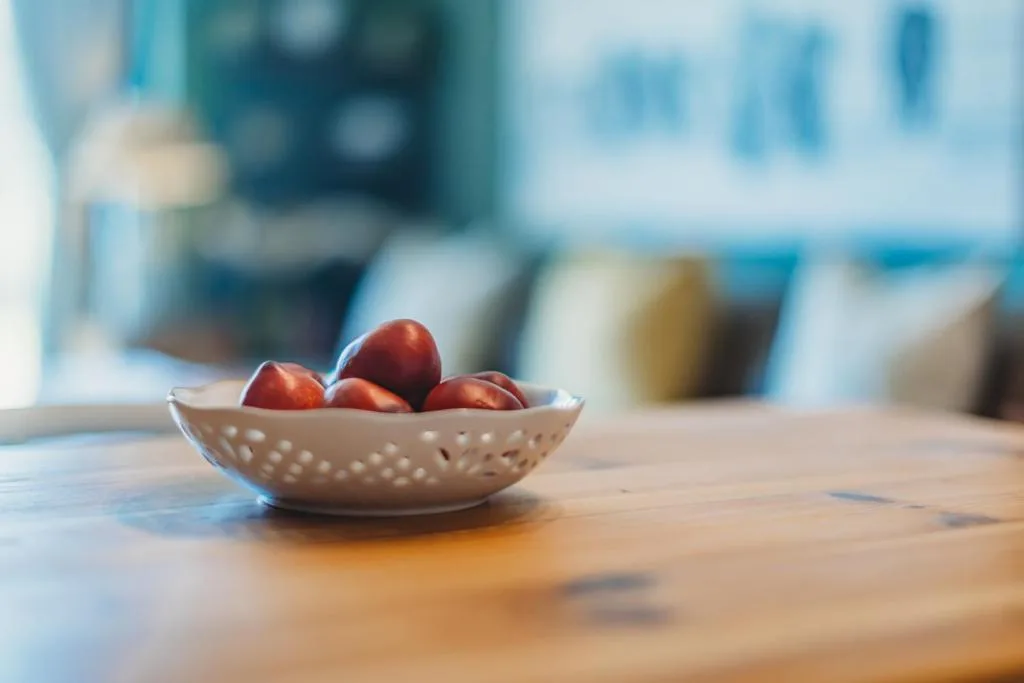 Fresh red apples in decorative ceramic bowl on wooden table