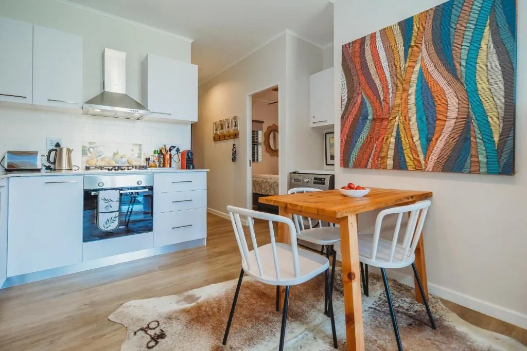 Modern dining area with wooden table, white chairs, and colorful wall art