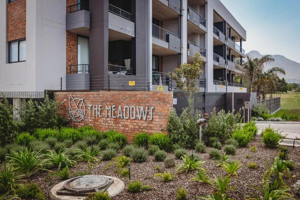 Modern apartment building with brick signage and landscaped gardens