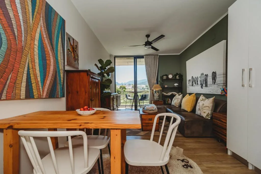 Open-plan lounge with dining table, sofa, and mountain views through glass doors