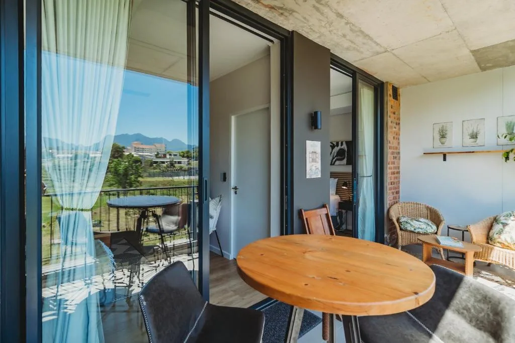 Open-plan lounge with wooden dining table, mountain views through glass doors