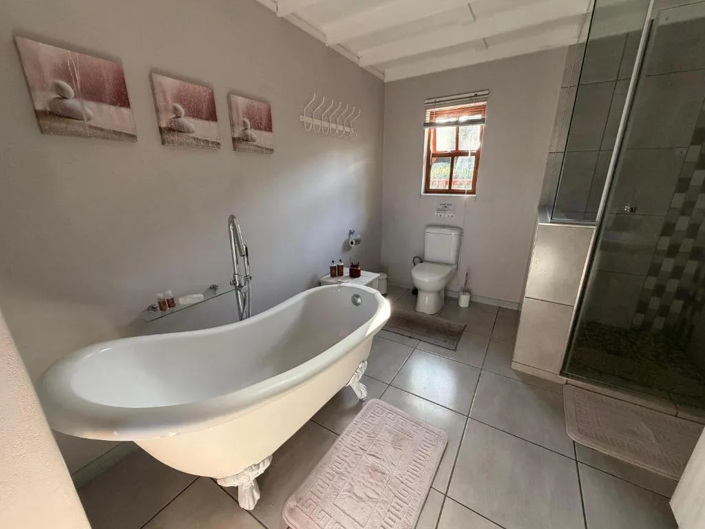 Spacious bathroom with freestanding bathtub, shower enclosure, toilet, and window