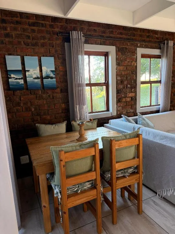 Bedroom with wooden chairs, brick wall, and garden views through windows