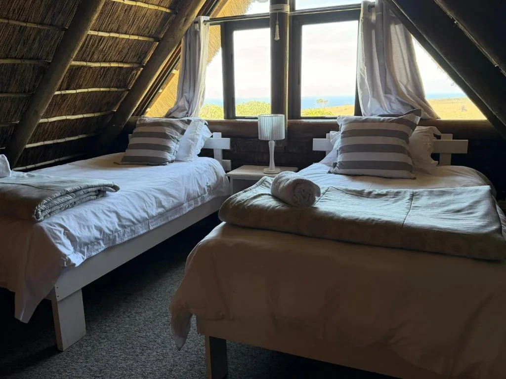 Cozy attic bedroom with two beds and ocean view through windows