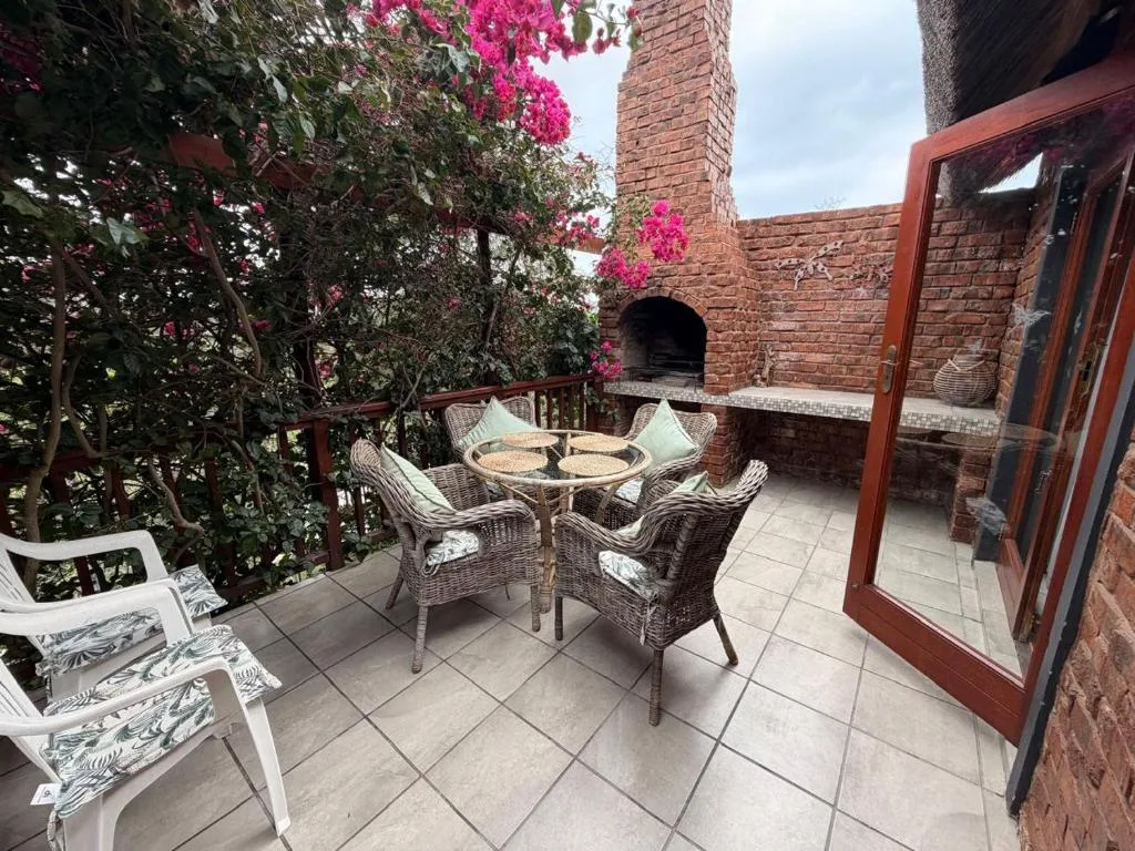 Outdoor patio with wicker seating, magenta bougainvillea, and brick fireplace