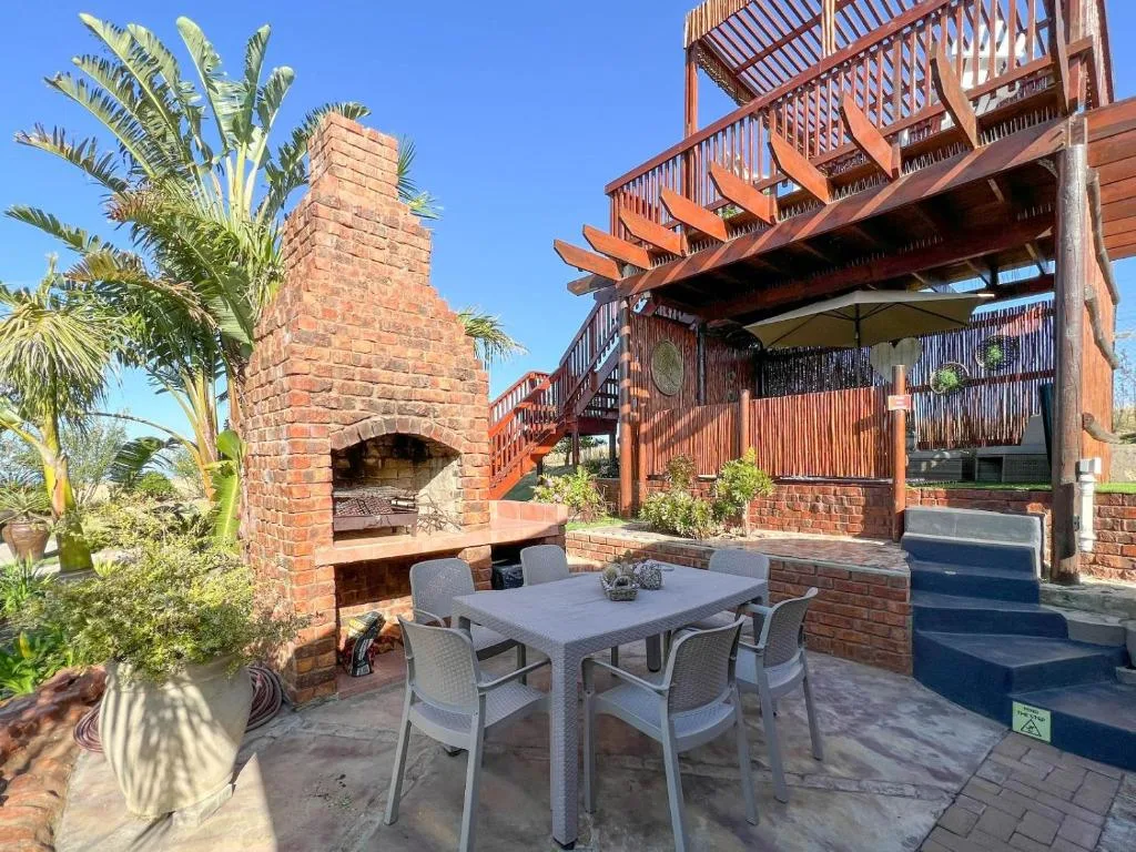 Outdoor patio with dining table, brick fireplace, and wooden pergola structure
