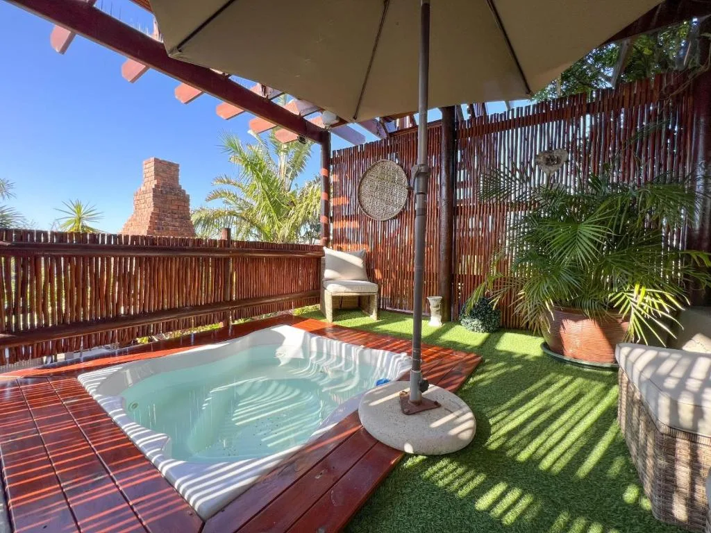 Shaded outdoor patio with hot tub and lounge seating area