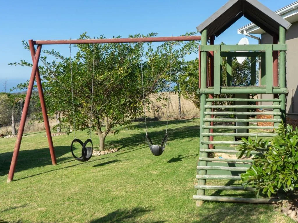 Garden swing set and green wooden play structure on manicured lawn