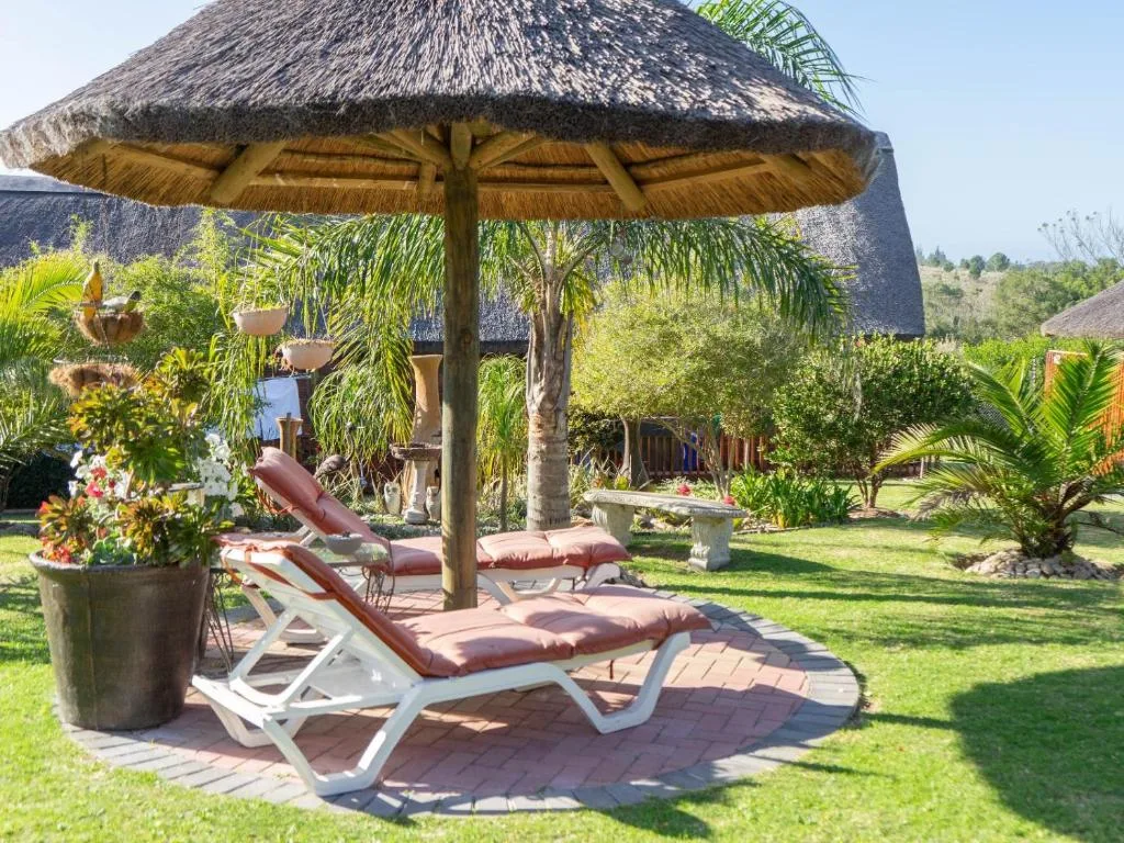 Thatched umbrella with loungers on manicured lawn garden area