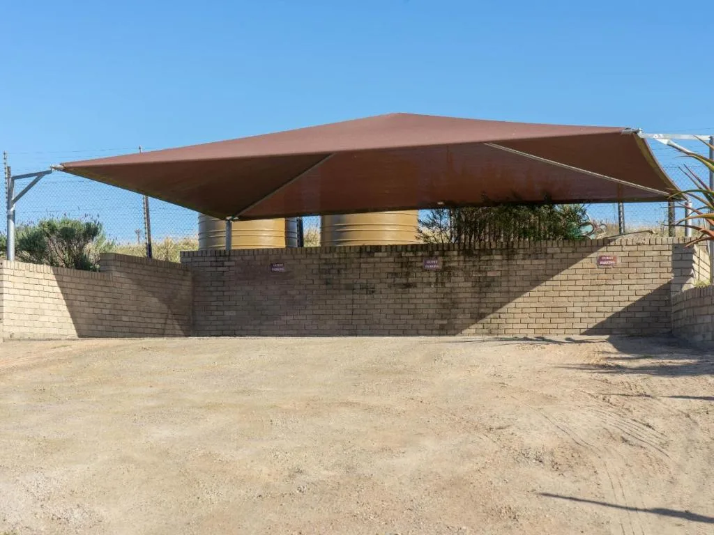 Outdoor braai area with brown shade sail and brick walls