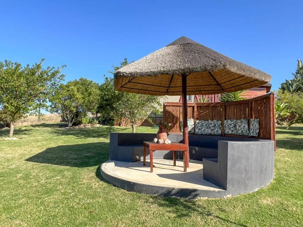 Thatched umbrella pavilion with seating area on manicured lawn
