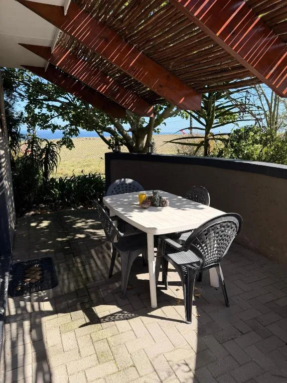 Covered patio with white dining table, black chairs, and vineyard views