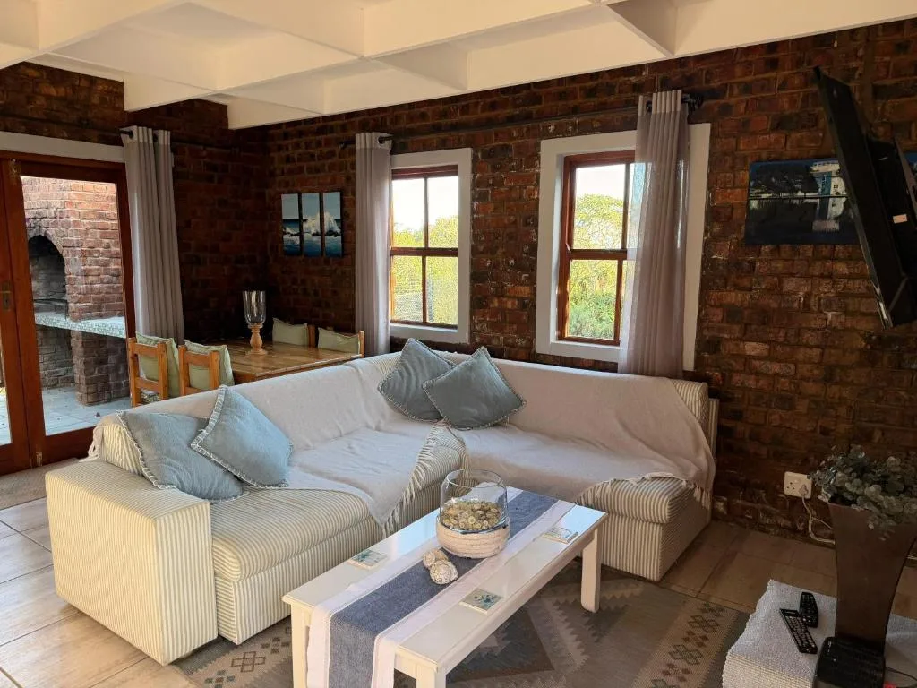 Spacious lounge with cream sectional sofa and exposed brick walls