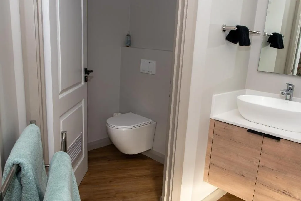 Modern bathroom with wall-mounted toilet, white basin vanity, and towel rack