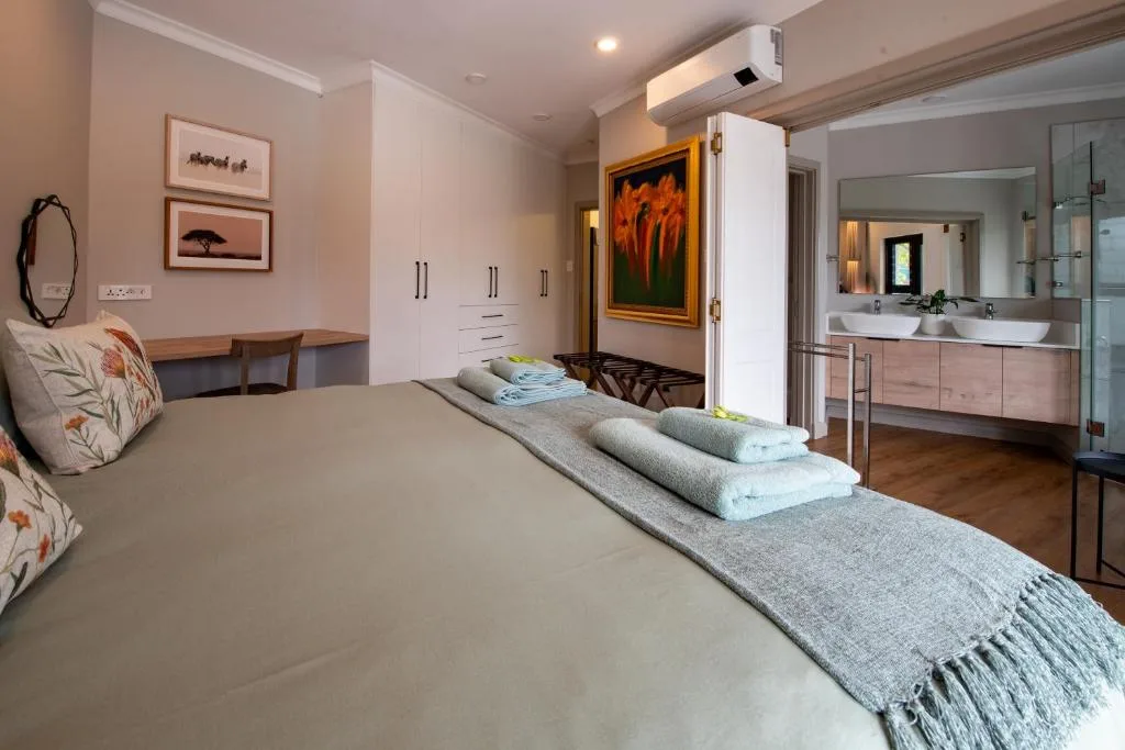 Spacious bedroom with queen bed, en-suite bathroom, built-in wardrobes, and artwork