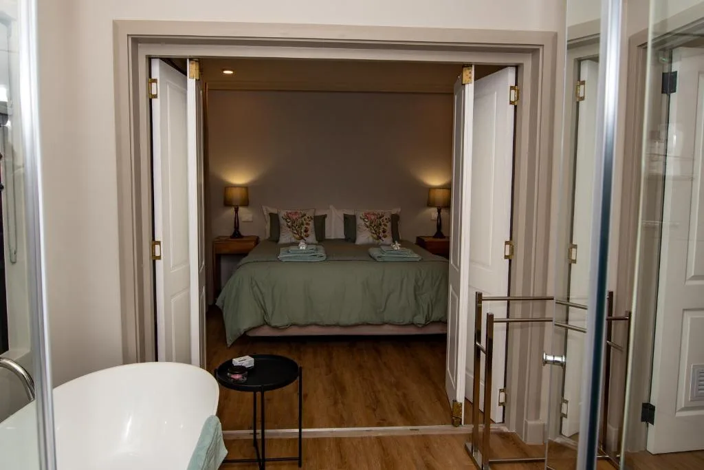Spacious bedroom with double bed, side tables, warm lighting, and ensuite bathroom view