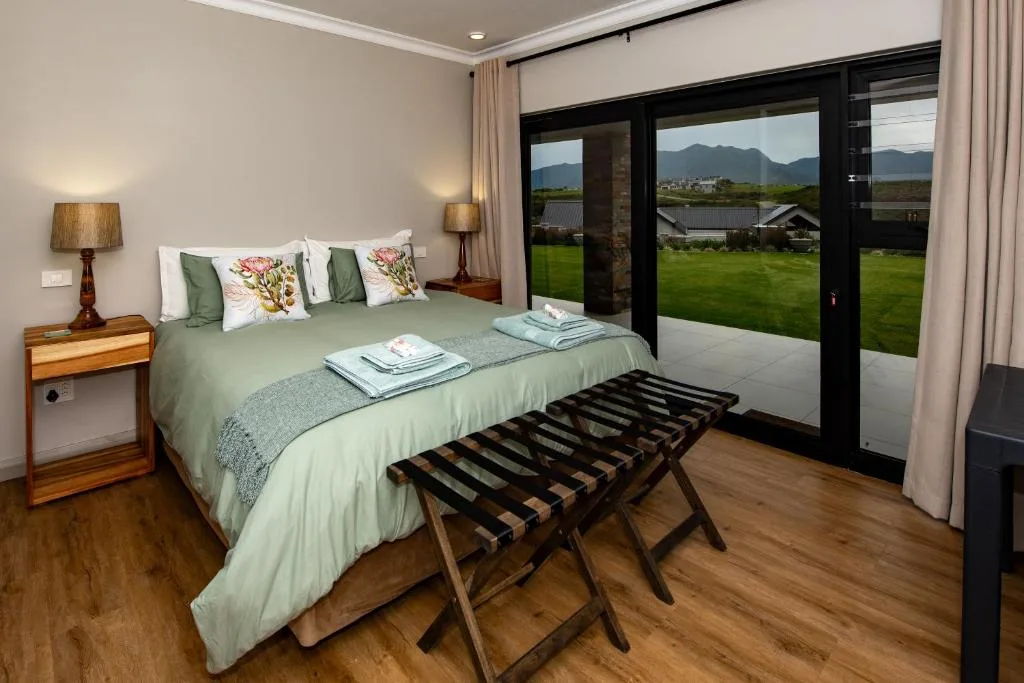 Modern bedroom with green bedding, mountain views through glass doors