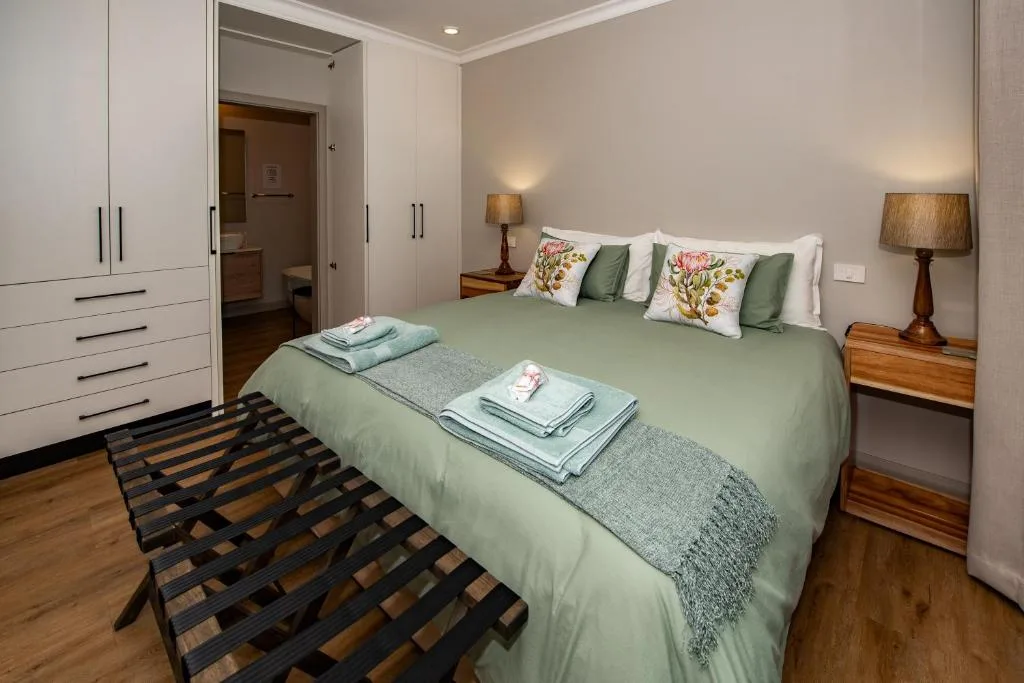 Spacious bedroom with green bedding, wooden nightstands, and built-in wardrobes