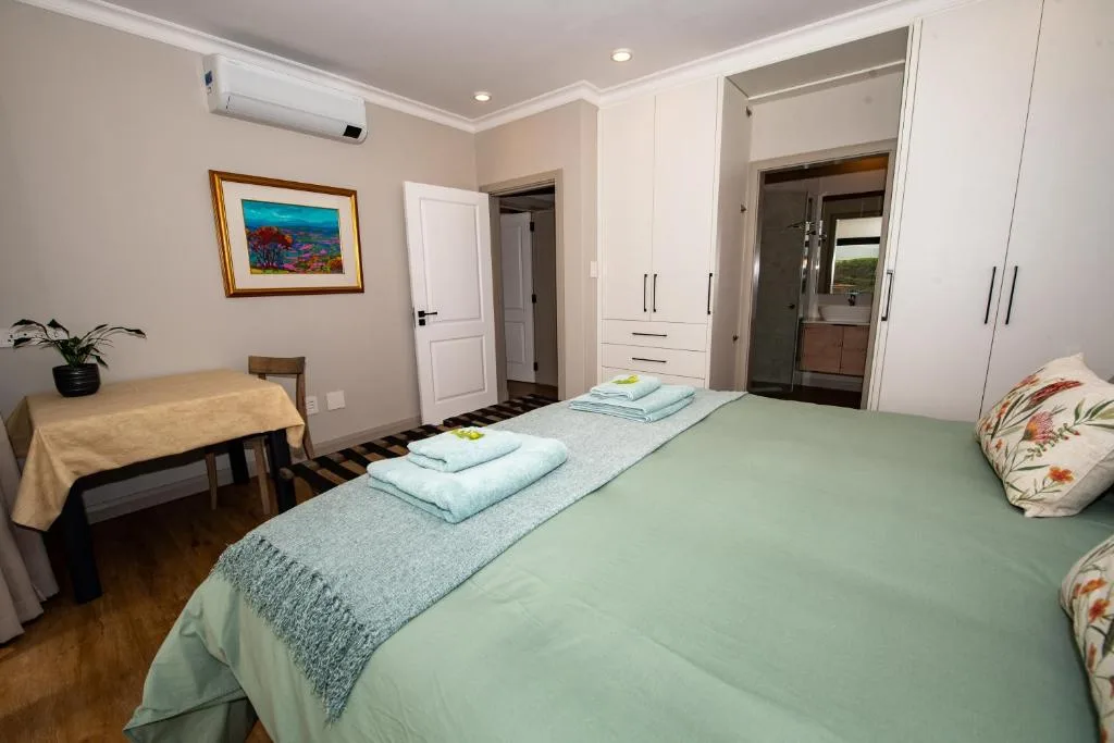 Spacious bedroom with green bed, white built-in wardrobes, and ensuite bathroom access