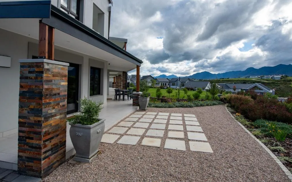 Modern home exterior with paved patio, mountain views, and manicured gardens