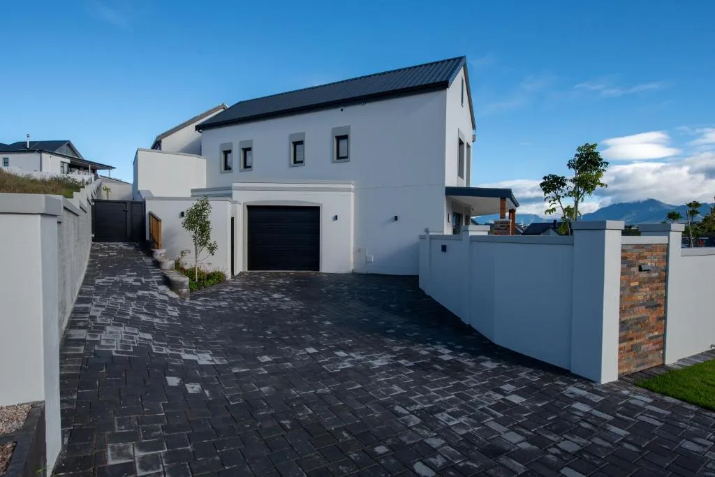 Modern white house with dark roof and paved driveway on Garden Route