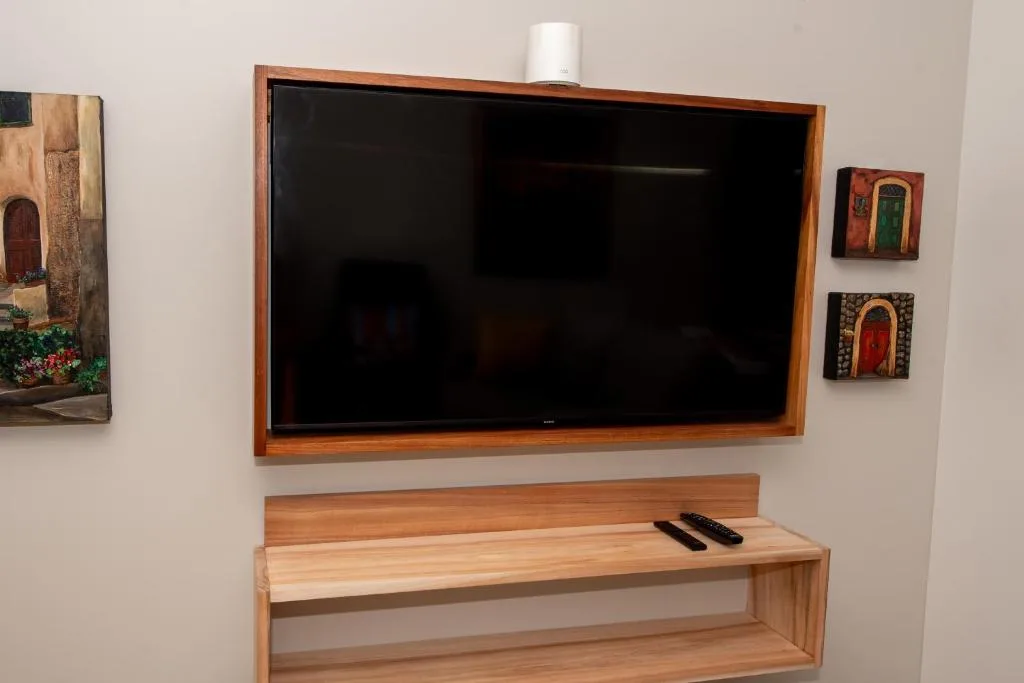 Wall-mounted flat-screen TV above wooden media console with decorative artwork