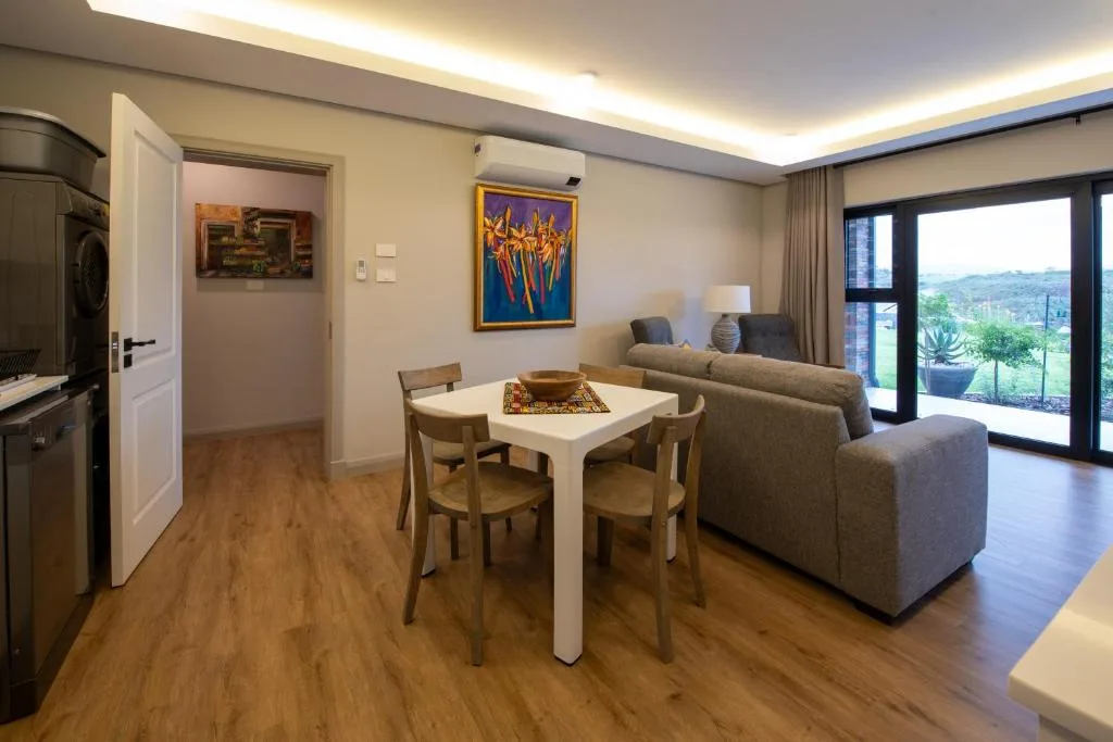 Open-plan living area with sofa, dining table, and scenic garden views