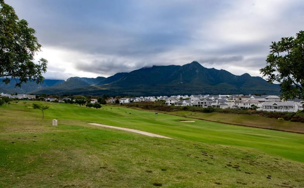 Majestic mountain peak framed by lush green golf course and white-walled homes