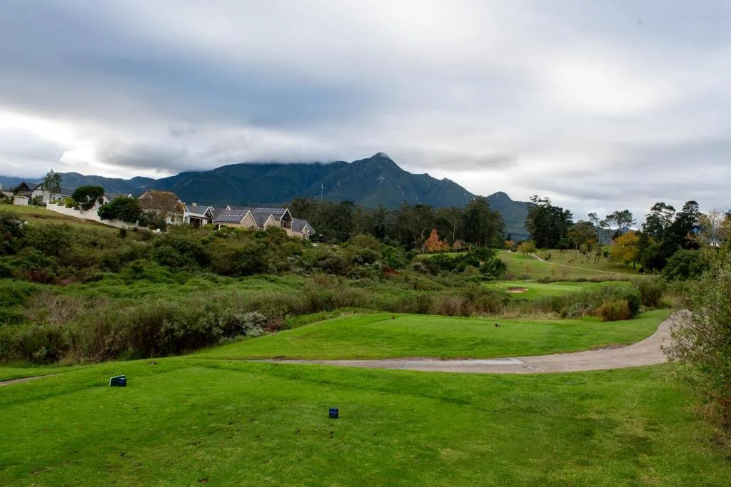 Lush green valley with mountain backdrop and residential homes visible