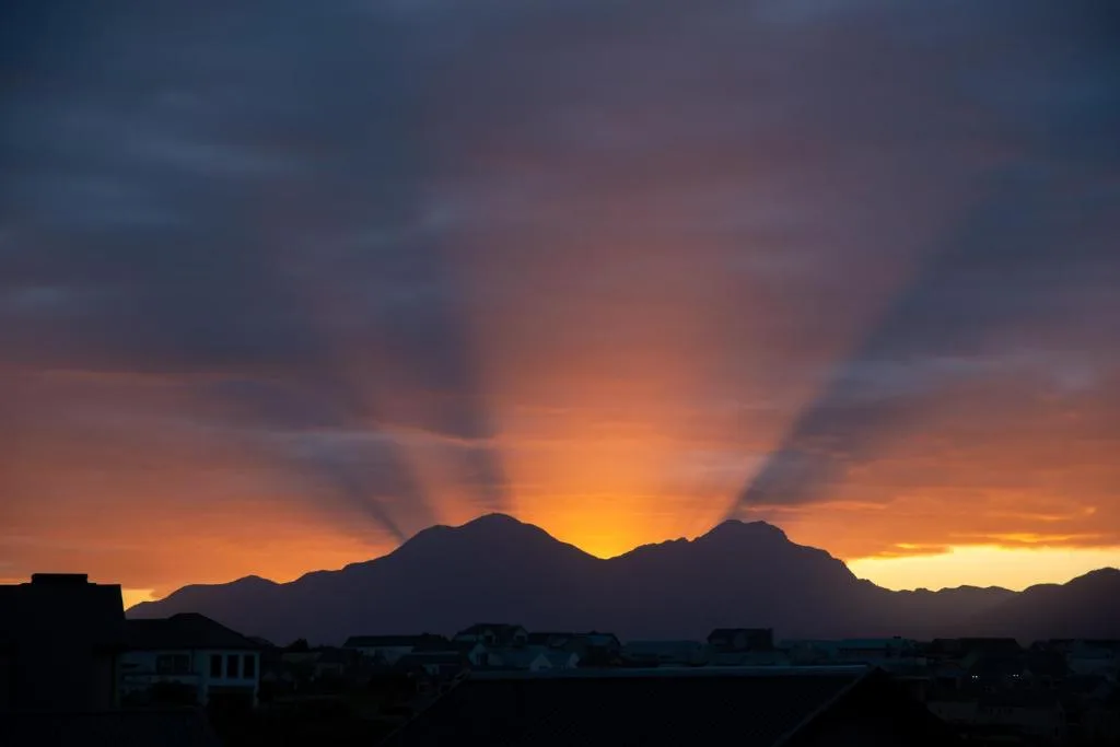 Dramatic sunset over mountains silhouetted against golden sky