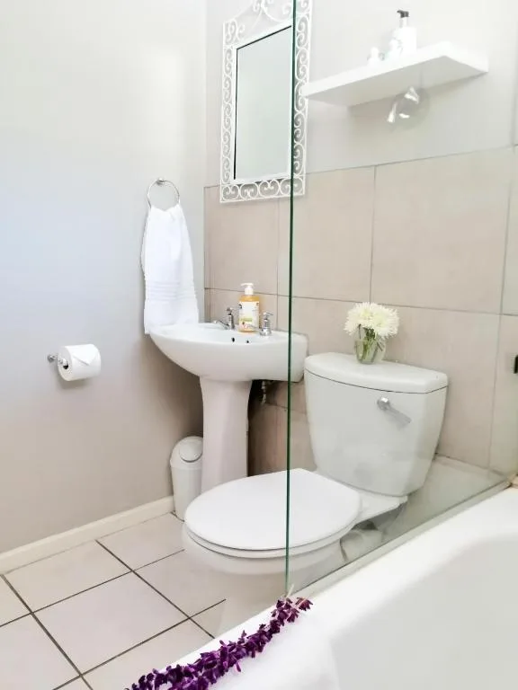Modern bathroom with pedestal sink, toilet, and glass shower enclosure