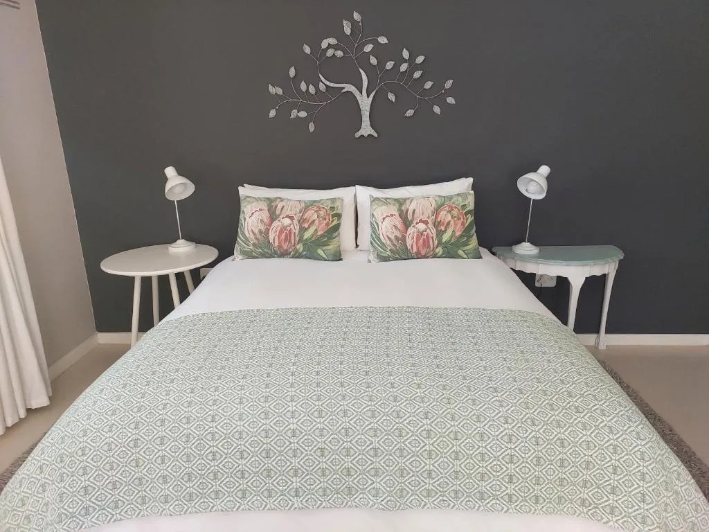 Elegantly styled bedroom with queen bed, decorative wall art, and floral pillows