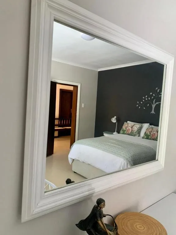 Bedroom with bed, dark accent wall, and decorative pillows visible in mirror