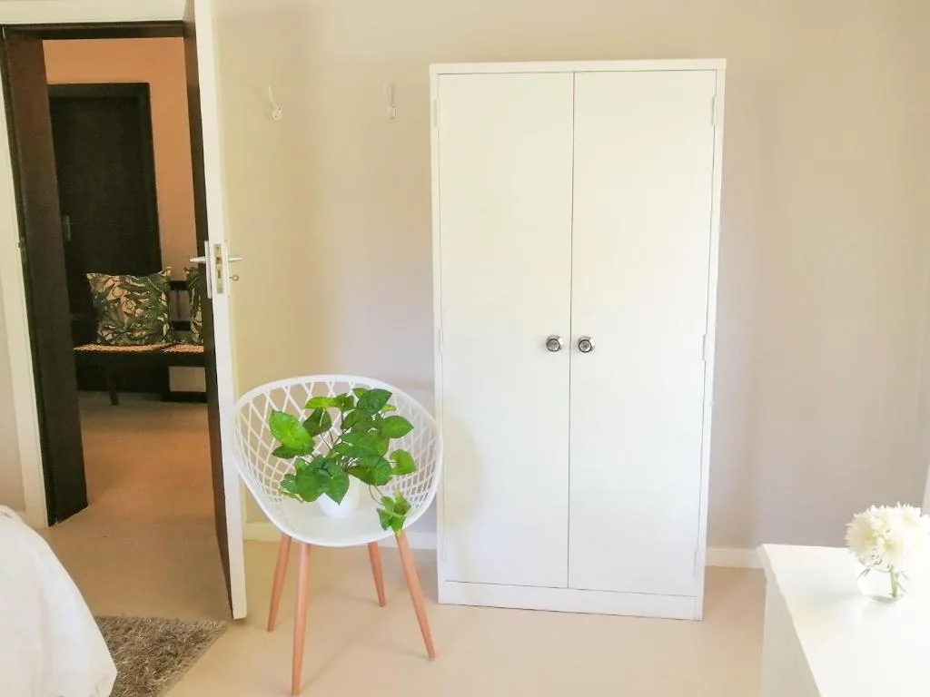 Spacious bedroom with white wardrobe, modern decor, and plant accent