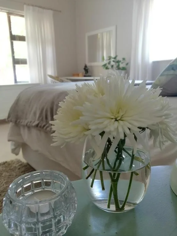 Bright bedroom with white flowers in vase on bedside table