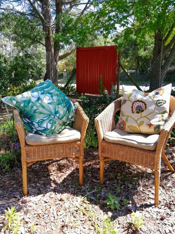 Two wicker chairs with colorful cushions on a shaded garden patio area