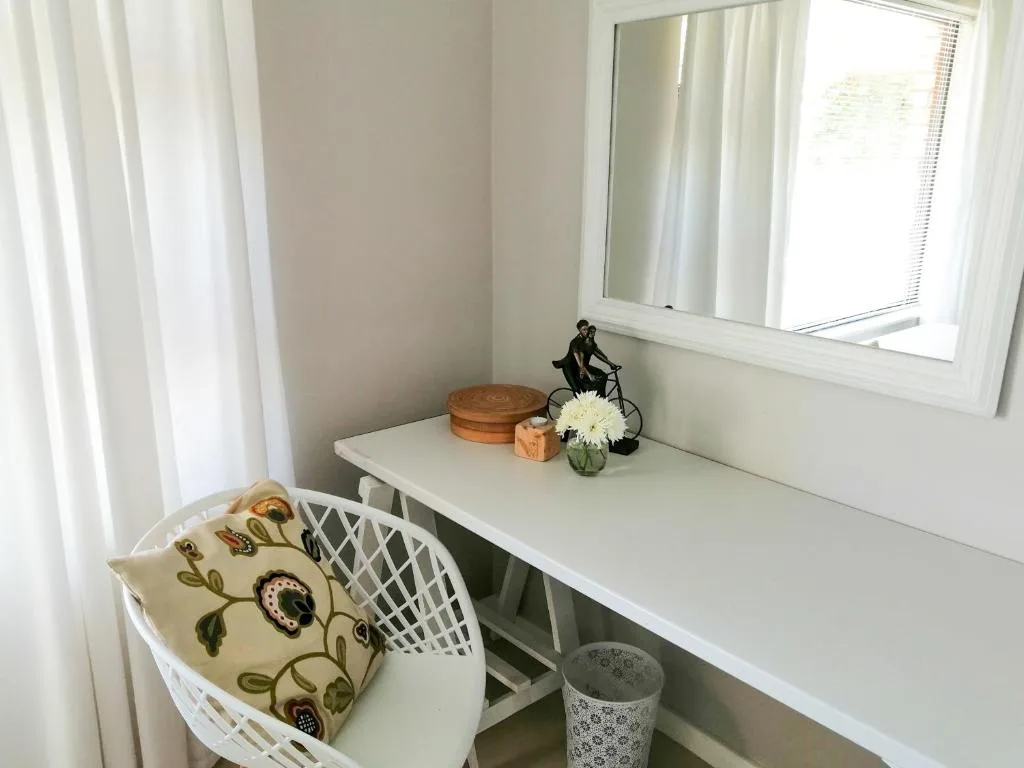 Minimalist white desk with decorative items and fresh flowers beside windows