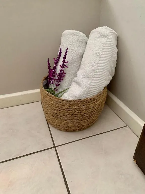Rolled white towels with purple flowers in woven basket