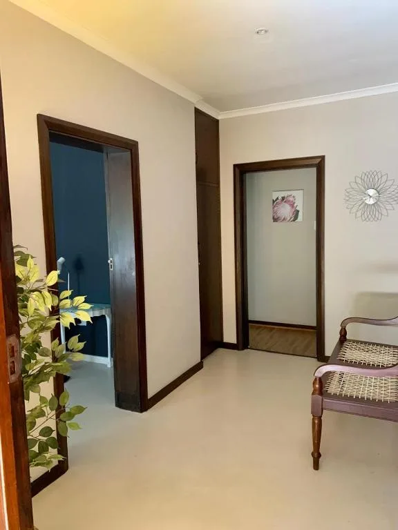 Hallway with cream walls, dark wooden doors, and decorative wall art