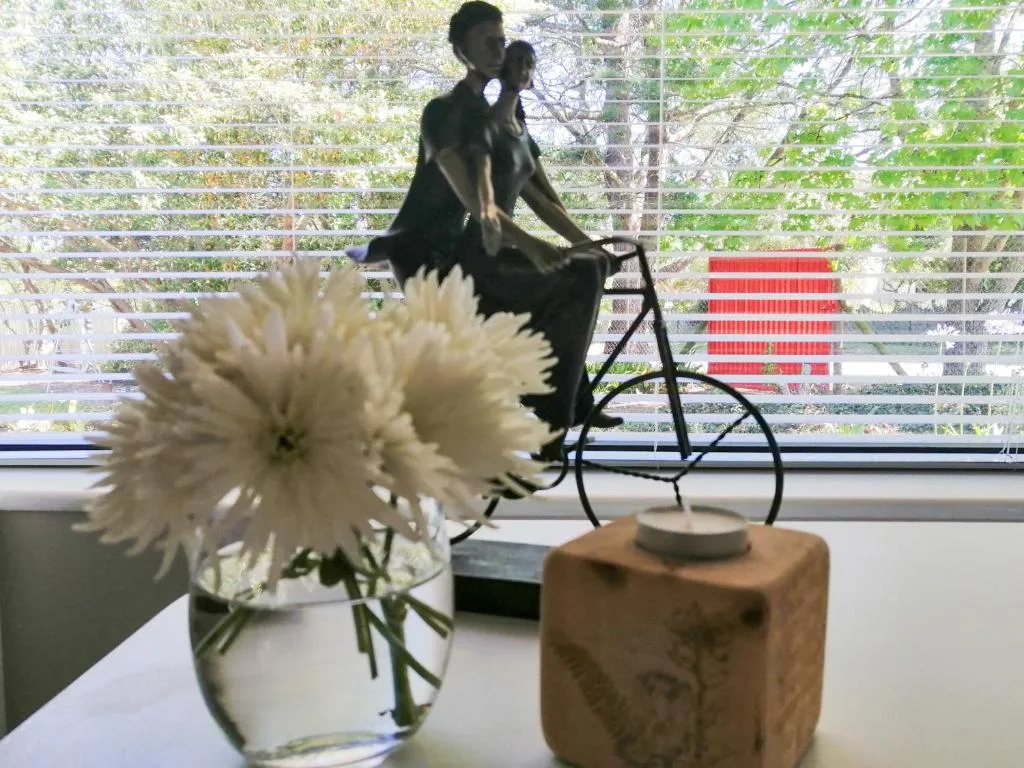 White gerbera flowers and decorative bike sculpture on windowsill
