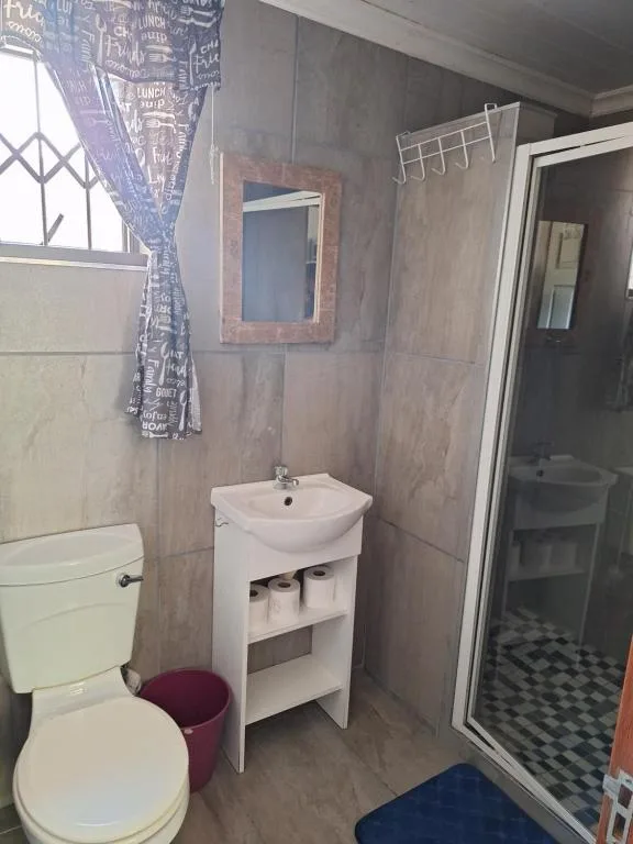 Bathroom with toilet, pedestal sink, mirror, and shower enclosure