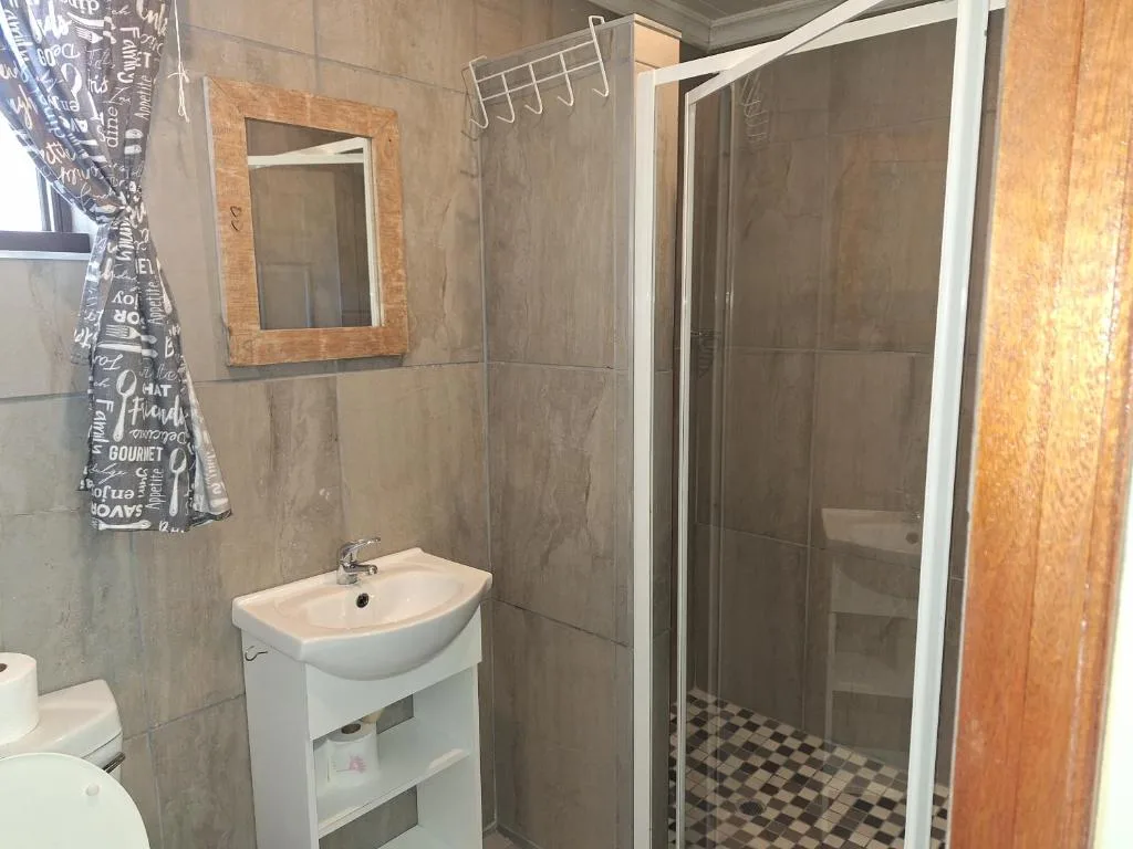 Modern bathroom with vanity sink, mirror, and enclosed shower cubicle