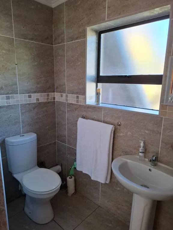 Bathroom with toilet, pedestal sink, and tiled shower enclosure